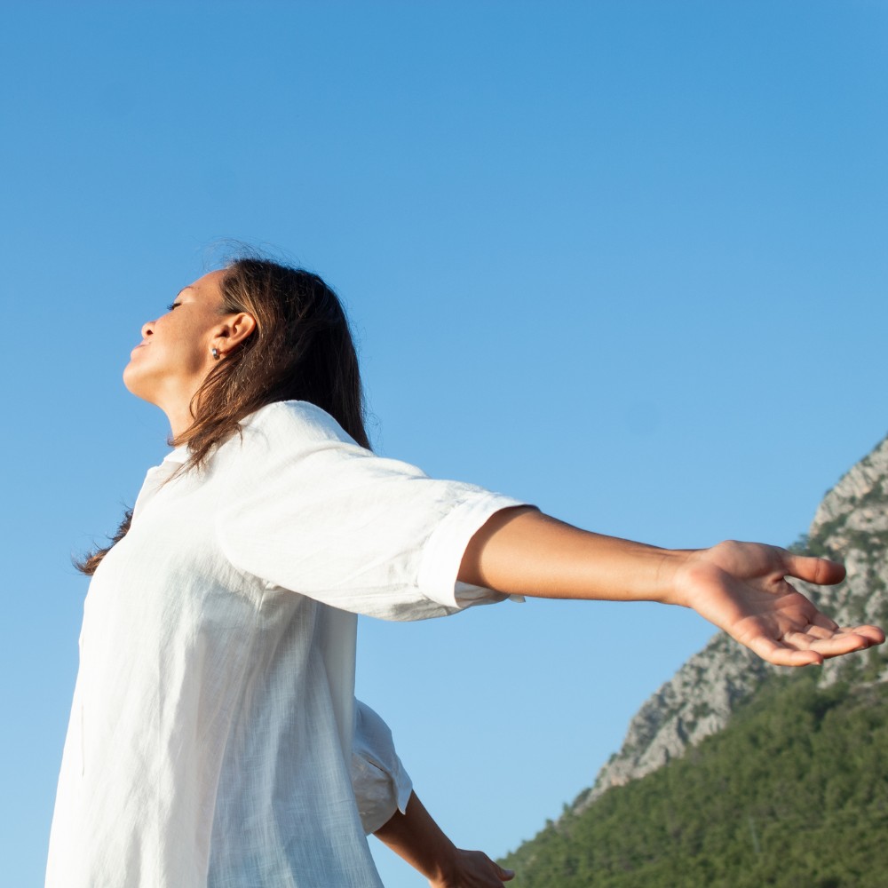 Woman with outstretched arms under blue sky