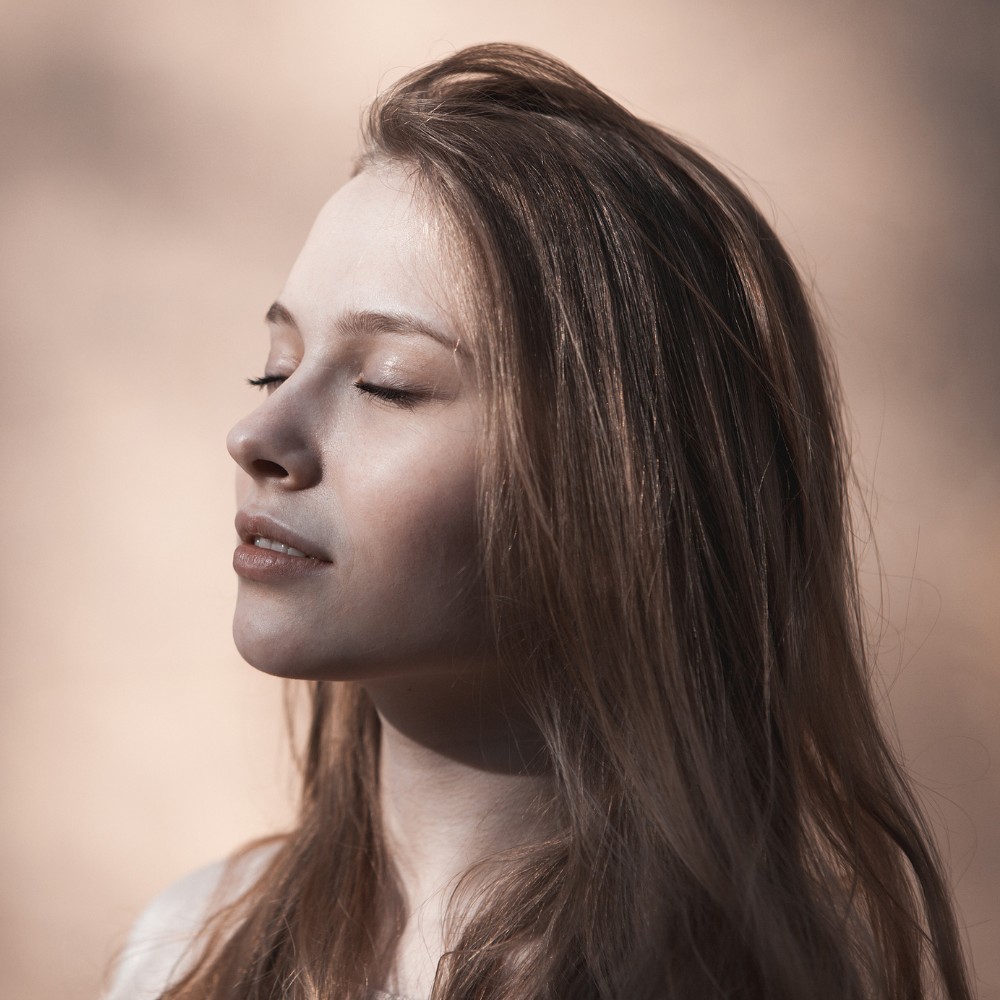 Woman with eyes closed having peaceful moment in soft sunlight