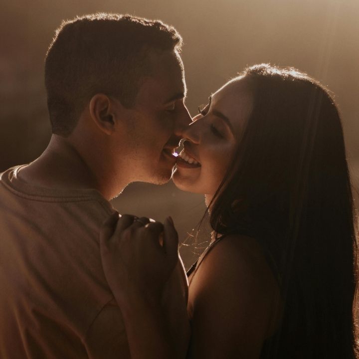 Couple standing close together about to kiss with warm backlighting